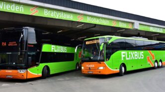 Два міжміські автобуси на перонах автовокзалу, над ними табло з назвами напрямків