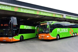 Два міжміські автобуси на перонах автовокзалу, над ними табло з назвами напрямків