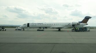 Регіональний реактивний літак у ліврі Lufthansa Regional на пероні аеропорту Жешув-Ясьонка, поруч наземний персонал і обслуговуюча техніка