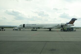 Регіональний реактивний літак у ліврі Lufthansa Regional на пероні аеропорту Жешув-Ясьонка, поруч наземний персонал і обслуговуюча техніка