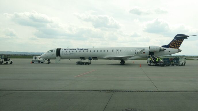 Регіональний реактивний літак у ліврі Lufthansa Regional на пероні аеропорту Жешув-Ясьонка, поруч наземний персонал і обслуговуюча техніка