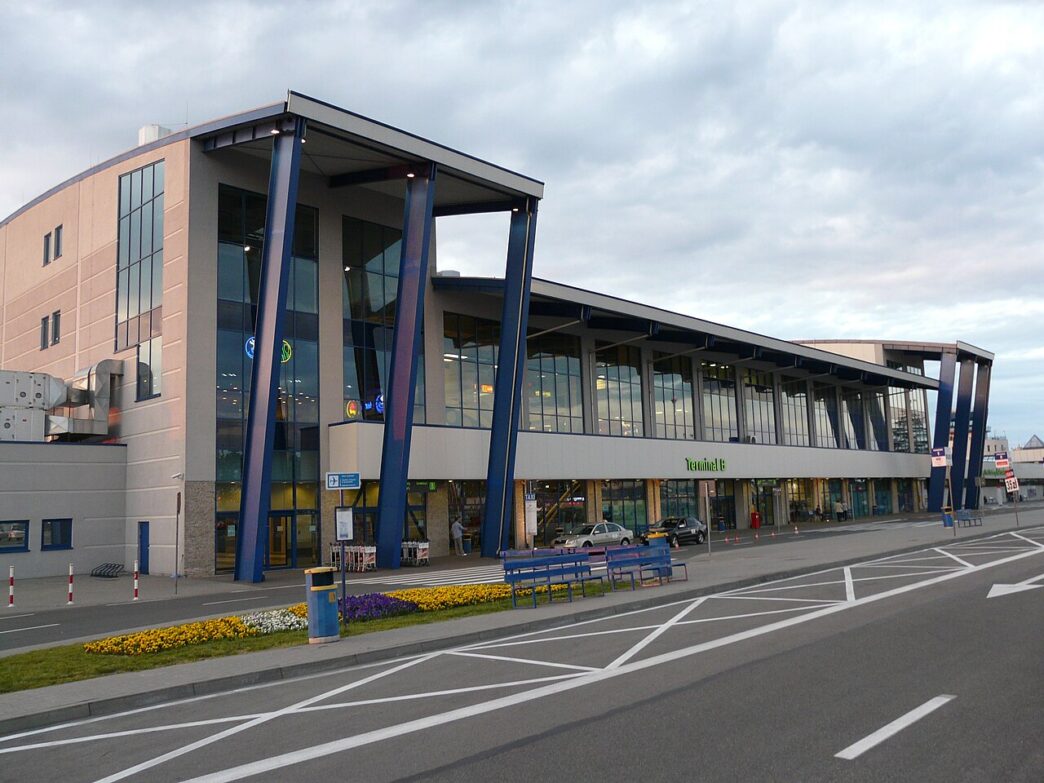 Фасад пасажирського терміналу аеропорту Катовіце-Пижовіце з під’їзною дорогою та клумбами