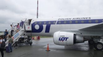 Пасажири спускаються трапом із реактивного літака у ліврі LOT на пероні аеропорту в похмуру погоду