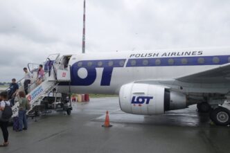 Пасажири спускаються трапом із реактивного літака у ліврі LOT на пероні аеропорту в похмуру погоду
