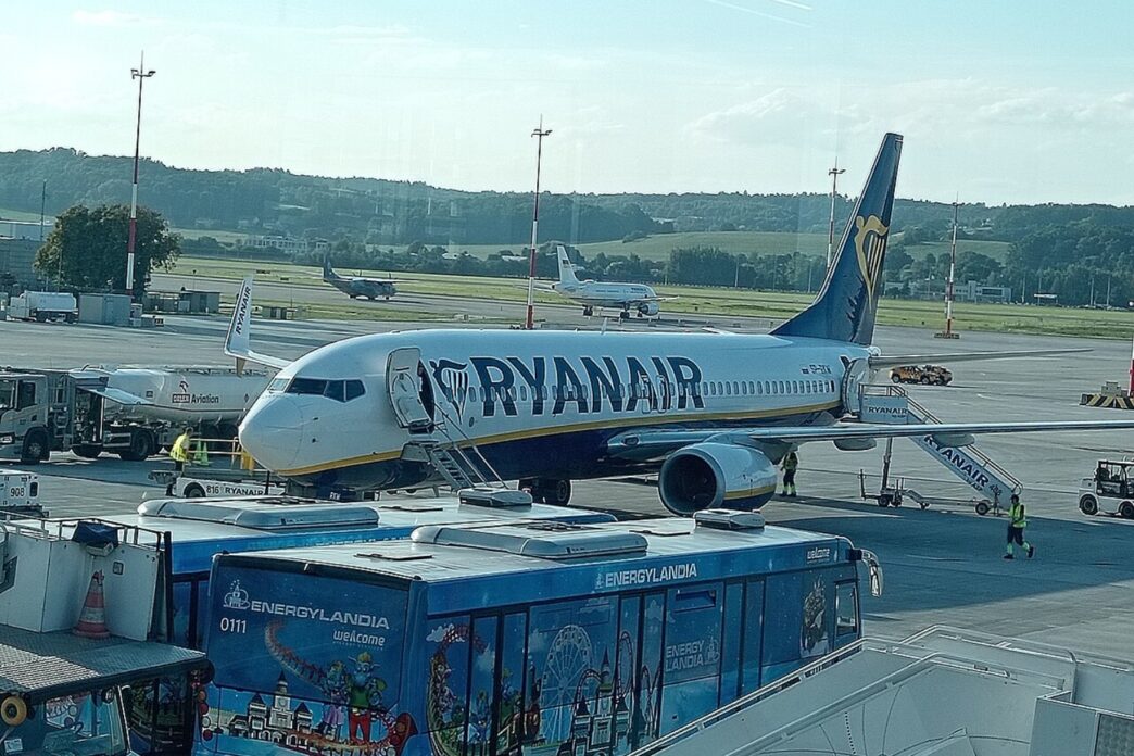 Літак Boeing 737 у ліврі Ryanair біля телетрапа на пероні аеропорту Краків-Балиці, поруч перонний автобус і наземний персонал, денне світло