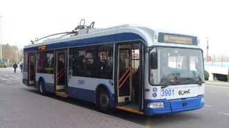 Синьо-білий тролейбус №30 на зупинці перед будівлею аеропорту, ліворуч на тротуарі пішоходи